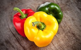 Colored bell peppers on wooden table